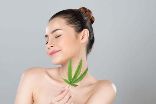 Closeup glamorous beautiful woman with soft make up and flawless smooth clean skin holding green leaf. Cannabis skincare cosmetic product for natural skin treatment concept in isolated background