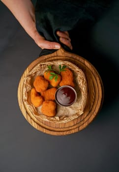 Top view of fried chicken fillet in breadcrumbs and sauce isolated on black background. Grilled chicken on a board in the hands of a waiter.Web banner text design.