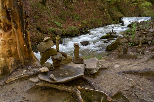 Pagan stones near stream of water in the mountain forest. Shipot waterfall in Carpathian mountains. Ukraine.