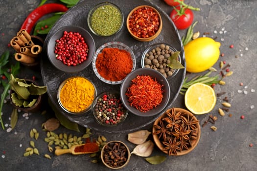 Multicolored herbs and spices for cooking. Indian spices. Against the background of black stone. View from above.