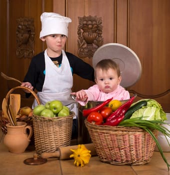 Portrait of a smiling babys sitting inside a large cooking stock pot surrounded by vegetables and food