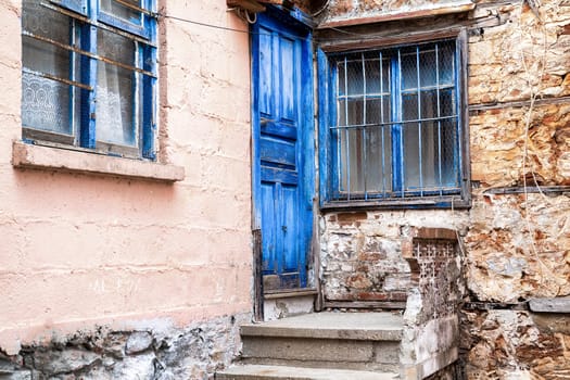 Porch of old village house with blue door and window.