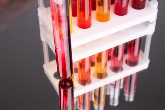 Close up red test tube on reflective surface. Colored laboratory test tubes with blood.