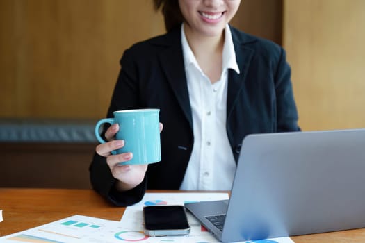 Portrait of a young woman drinking coffee while using a computer.