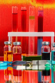 Collection of drug vials on red background. Scientific lab medicine reserarch.