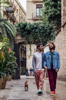 gay male couple walking with his dog along a beautiful ancient street decorated with plants, concept of leisure and love between people of the same sex