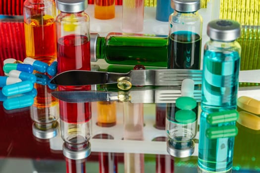 Close up colored drug vials with medicine solution. Lab drugs on reflective surface.