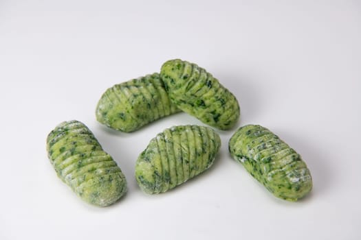 Pile of green spinach gnocchi dough dumplings isolated over the white background, High quality photo