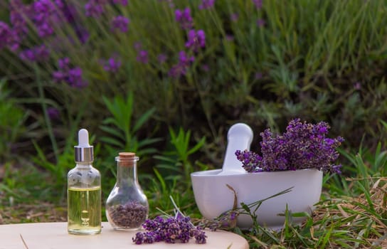 jars with lavender oil, lavender flowers, on the background of a lavender field. Selective focus