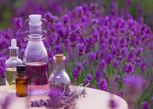 jars with lavender oil, lavender flowers, on the background of a lavender field. Selective focus