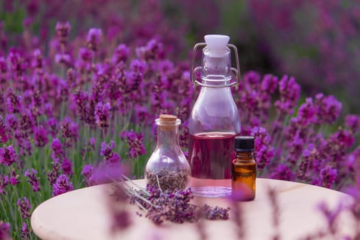 jars with lavender oil, lavender flowers, on the background of a lavender field. Selective focus