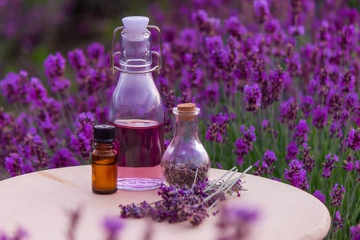 jars with lavender oil, lavender flowers, on the background of a lavender field. Selective focus
