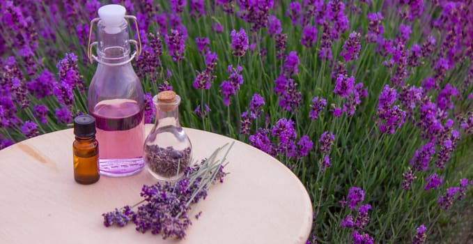 jars with lavender oil, lavender flowers, on the background of a lavender field. Selective focus