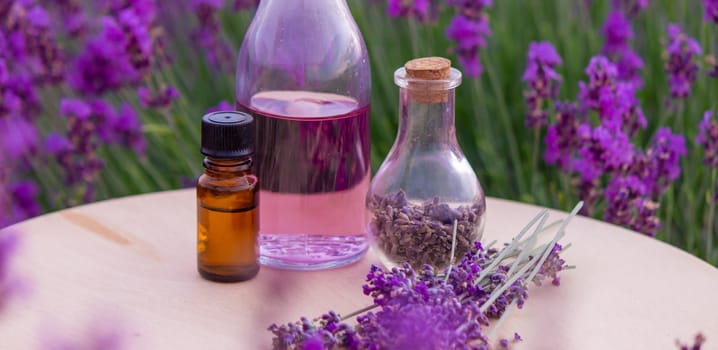 jars with lavender oil, lavender flowers, on the background of a lavender field. Selective focus