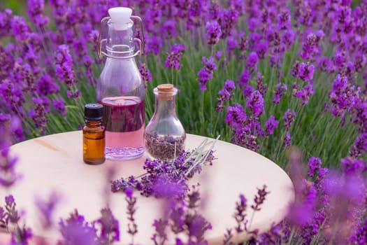 jars with lavender oil, lavender flowers, on the background of a lavender field. Selective focus