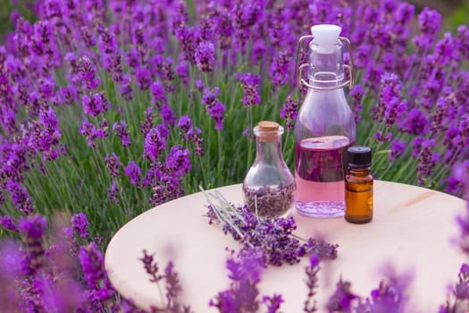 jars with lavender oil, lavender flowers, on the background of a lavender field. Selective focus
