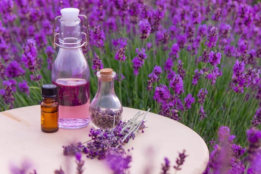 jars with lavender oil, lavender flowers, on the background of a lavender field. Selective focus