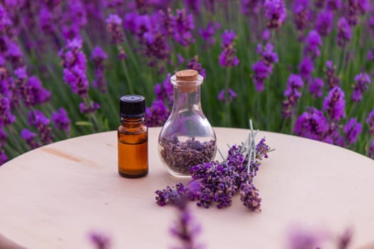 jars with lavender oil, lavender flowers, on the background of a lavender field. Selective focus