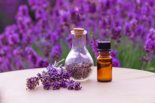 jars with lavender oil, lavender flowers, on the background of a lavender field. Selective focus