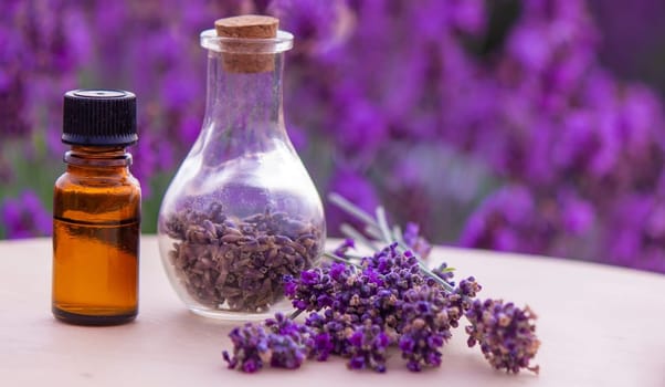 jars with lavender oil, lavender flowers, on the background of a lavender field. Selective focus