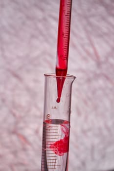 Close up pipette dropping blood into test tube. Blood test and analysis in medical research laboratory.