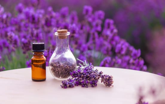 jars with lavender oil, lavender flowers, on the background of a lavender field. Selective focus