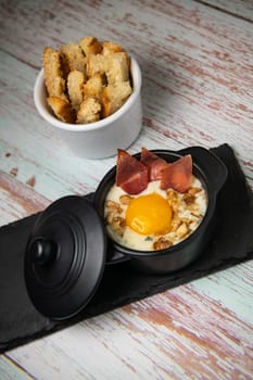 Recipe Oeuf cocotte with fresh cream sauce, Roquefort and walnuts, ham chips, toasted bread sticks. High quality photo