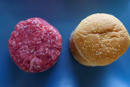 top view of a pile of raw beef burgers with their buns on a blue plate