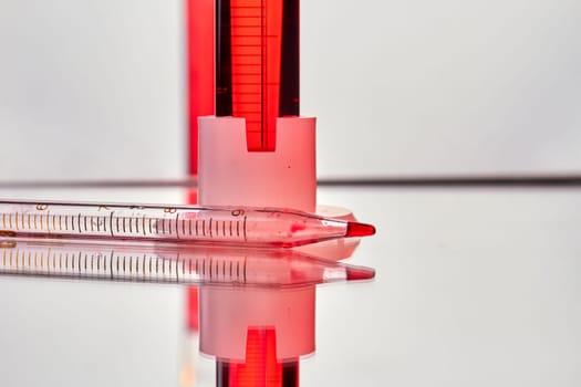 Close up pipette with blood sample on reflective surface. Blood test and analysis in medical research laboratory.