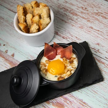 Recipe Oeuf cocotte with fresh cream sauce, Roquefort and walnuts, ham chips, toasted bread sticks. High quality photo