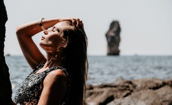 Woman travel sea. Young Happy woman in a long red dress posing on a beach near the sea on background of volcanic rocks, like in Iceland, sharing travel adventure journey