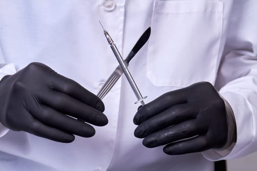 Doctor surgeon holds a scalpel with syringe. Surgical concept instrument.