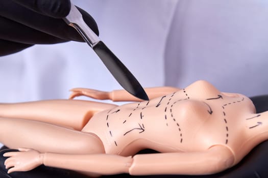 Close up scalpel cutting plastic dolls body. Dotted lines on the body.