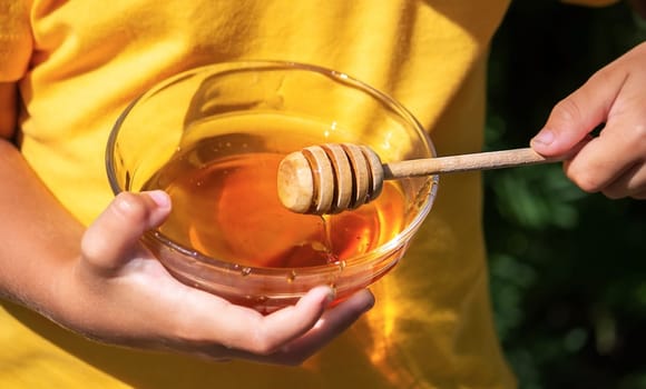 a child eats honey in the garden from a transparent bowl. nature selective focus