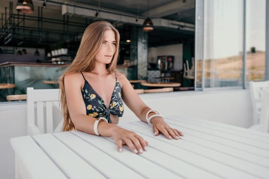 Happy woman portrait in cafe. Boho chic fashion style. Outdoor photo of young happy woman with long hair, sunny weather outdoors sitting in modern cafe