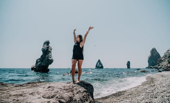 Woman travel sea. Young Happy woman in a long red dress posing on a beach near the sea on background of volcanic rocks, like in Iceland, sharing travel adventure journey