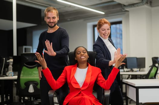 Caucasian red-haired woman, bearded caucasian man high five african american young woman in the office
