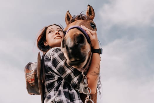 Cute happy young woman with horse. Rider female drives her horse in nature on evening sunset light background. Concept of outdoor riding, sports and recreation.