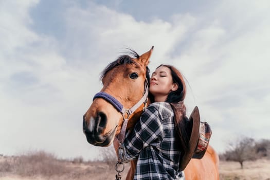 Cute happy young woman with horse. Rider female drives her horse in nature on evening sunset light background. Concept of outdoor riding, sports and recreation.