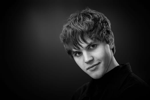 close-up portrait of positive handsome man looking at the camera on black background. black and white. copy space