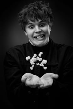 portrait of crazy young man throwing up popcorn and grimacing . black and white