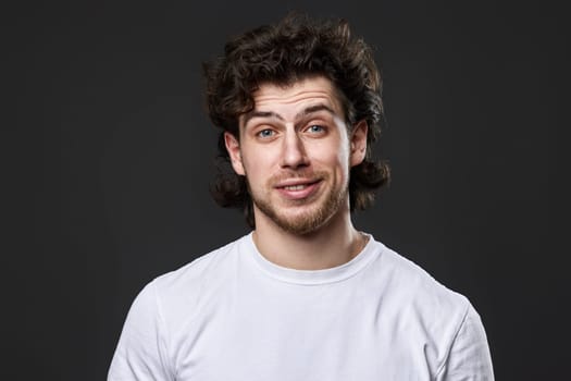 skeptic and nervous man in white t-shirt with disapproving expression on face on dark gray background