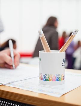 Close up of pencil box, in the background caucasian hand fill a form