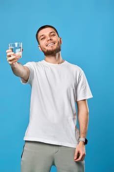 happy smiling handsome man offering a glass of water on blue background.