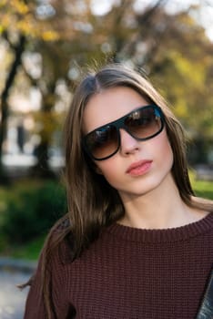 Close up shot of stylish young woman in sunglasses at the street. Beautiful female model.