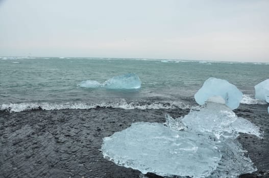 Crystal clear ice chunks at Diamond beach with black sand in Fellsfjara, Jokulsarlon on Iceland