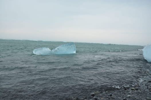 Crystal clear ice chunks floating on the waves of Diamond beach in Fellsfjara,Jokulsarlon on Iceland