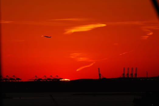 Silhouette of Statue of Liberty and Liberty Island in New York against an orange sunset sky