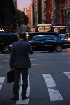 Back shot of businessman in New York in suit talking on cell phone on the streets of New York City, US