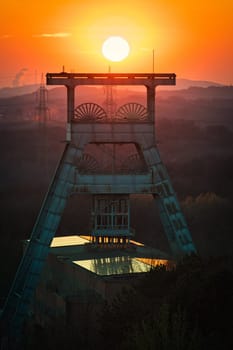 Vertical shot of a headframe tower with a golden sun setting in the background in Herten, Germany